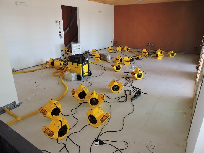 Ventilatori e deumidificatori professionali al lavoro in un locale allagato