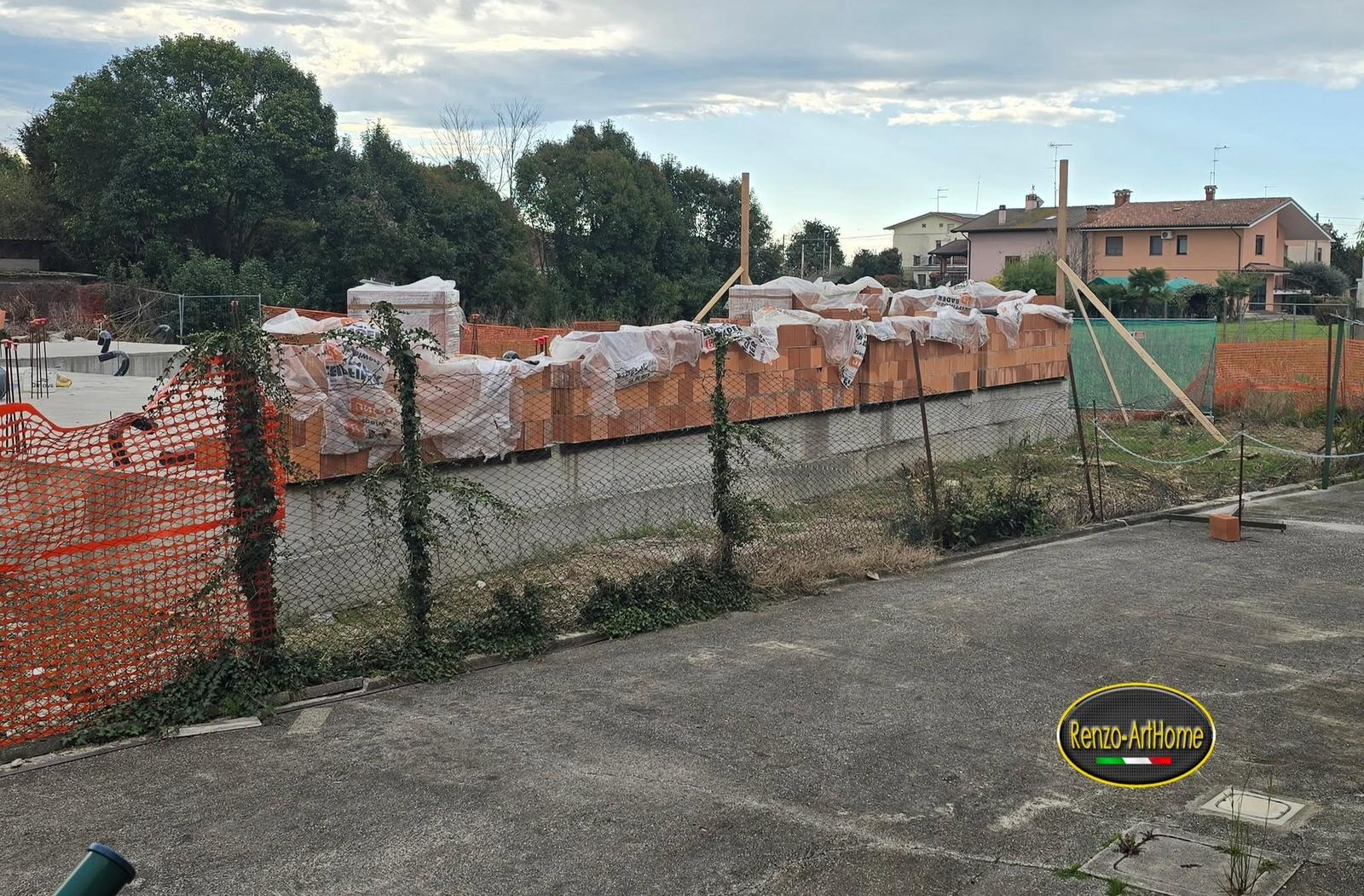 Muro perimetrale in blocchi di laterizio con la sommità coperta dai teli, a fine giornata di cantiere