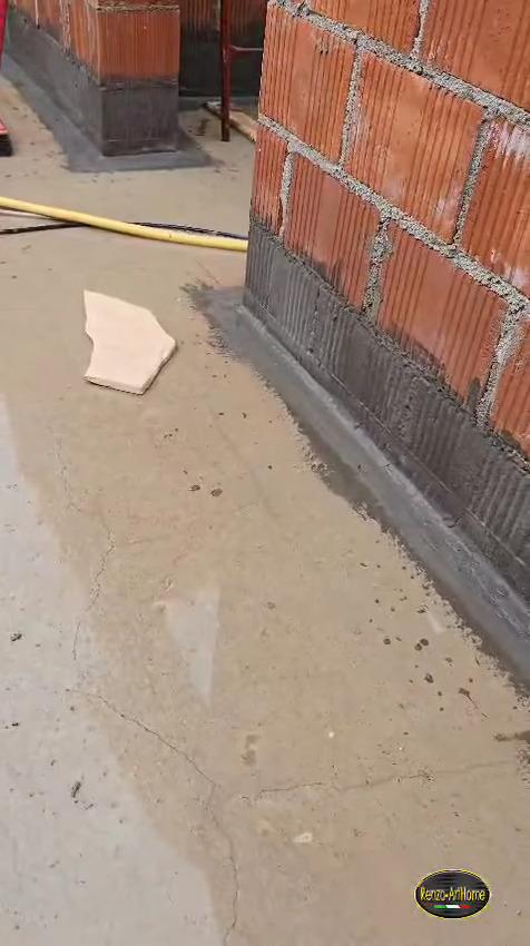 Base delle murature interne trattata con guaina cementizia e risvolto sul piano, in un cantiere al grezzo