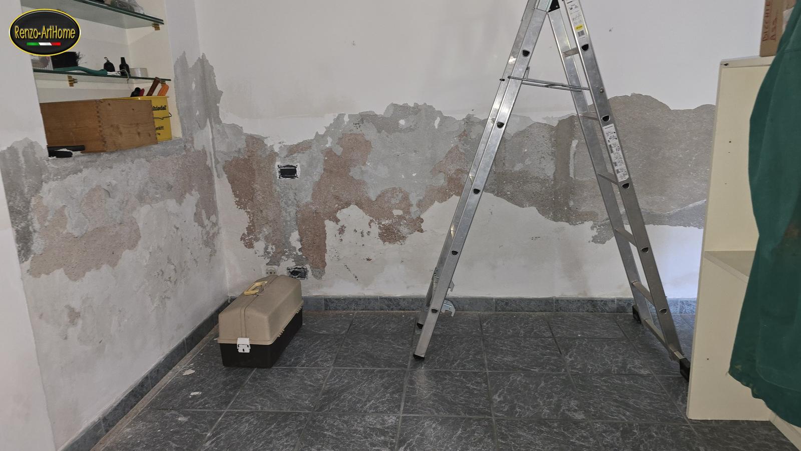 La fascia bassa di una parete del cantiere con l'intonaco sfogliato dalla risalita