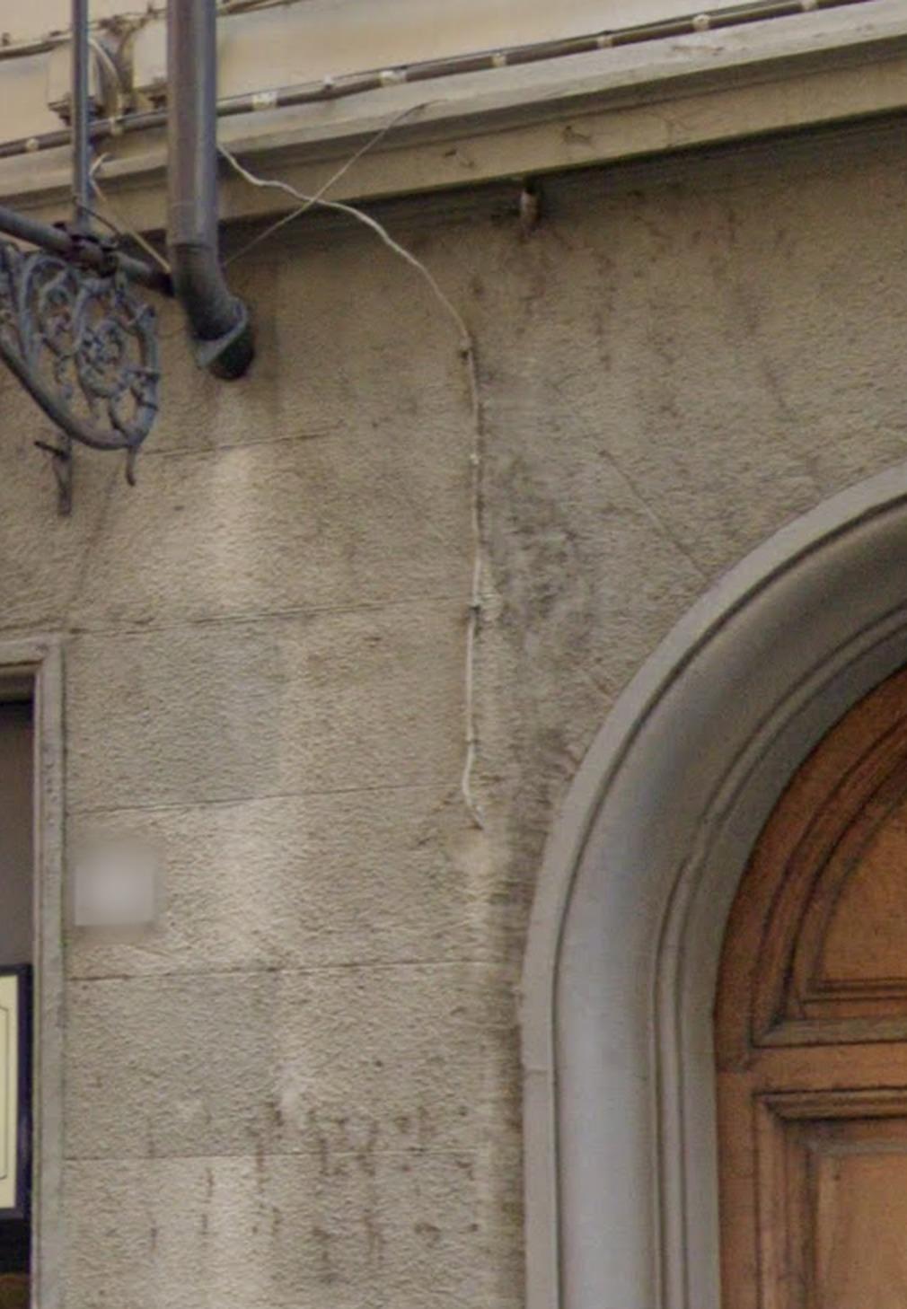 Tratto di pluviale che si chiude nella muratura, con la parete scura sotto l'imbocco