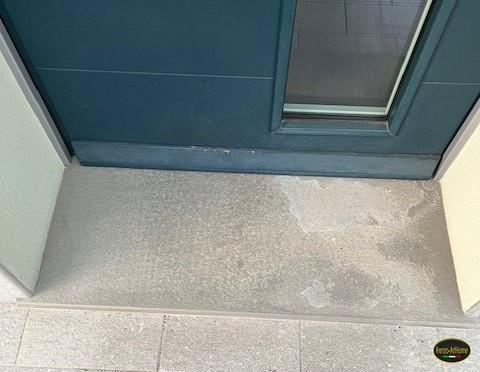 Soglia di una porta di ingresso con una chiazza chiara estesa su una parte della lastra