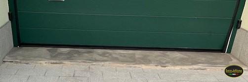 Soglia di un garage con macchie scure che seguono l'andamento delle fughe