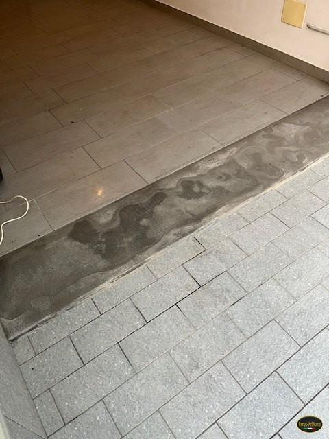 La stessa soglia di garage vista per intero, fra la pavimentazione interna e quella esterna, con degrado esteso